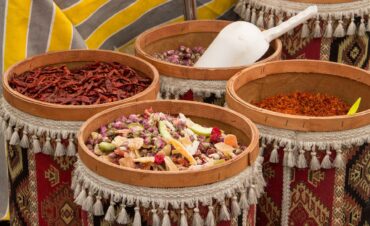 Cestas decorativas con borlas que contienen diferentes especias secas: guindillas, pétalos de rosa, mezcla de frutas deshidratadas y hilos de azafrán.